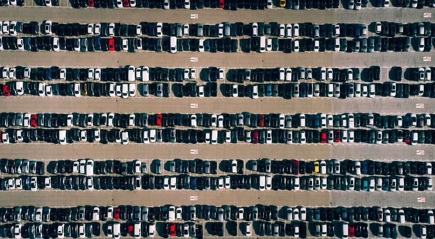 Luftaufnahme eines großen Gebrauchtwagen-Parkplatzes mit hunderten Fahrzeugen in Reihen